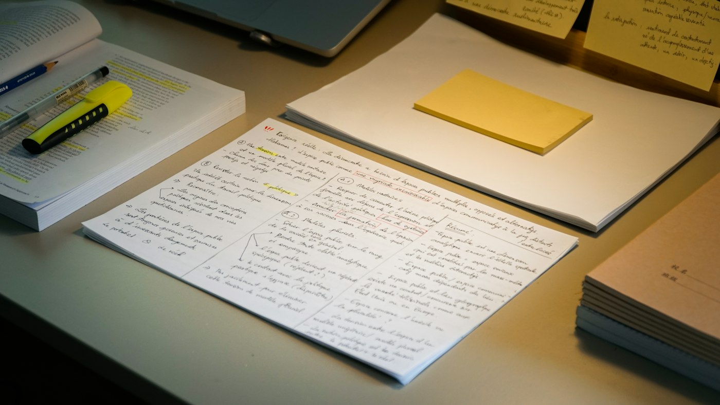 Notes et documents de candidature organisés méthodiquement sur un bureau