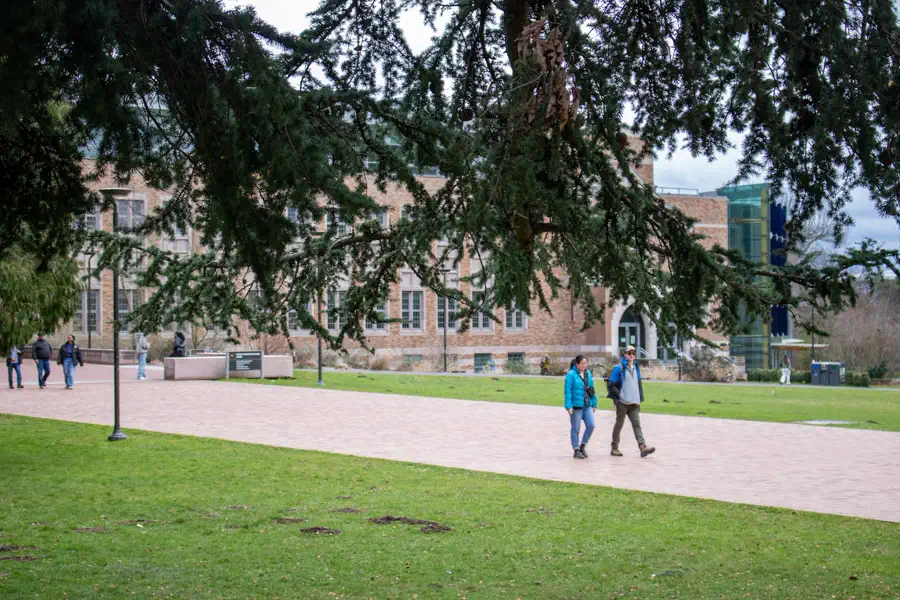 Étudiants marchant sur un campus universitaire, bâtiment en pierre en arrière-plan